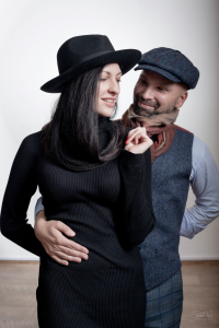 Женщина в черной фетровой шляпе Федора с кожаным ободком Tonak. Мужчина в синей клетчатой твидовой кепке-восьмиклинке Келлс Hanna Hats